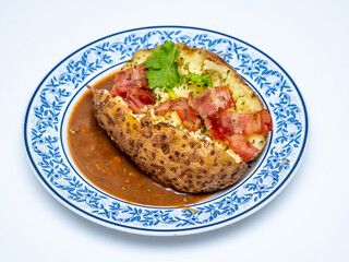 Baked Potatoes with Gravy and Bacon on white plate and white background.