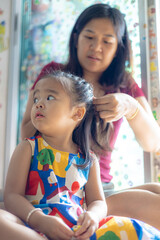 Obraz premium Beautiful asian mom with adorable daughter hair dressing in cozy room