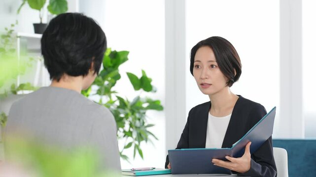 オフィスで会話する二人の女性ビジネスパーソン