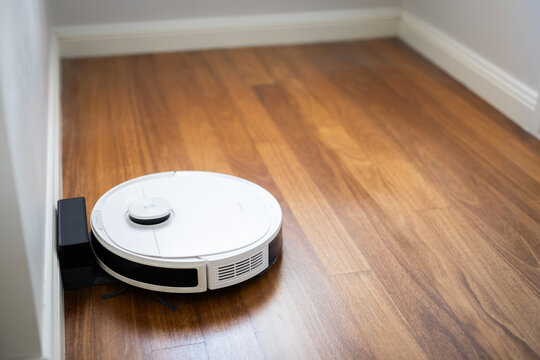 white robot vacuum cleaner timber floors charging doc bedroom cleaning helping household duties tasks chores automatic