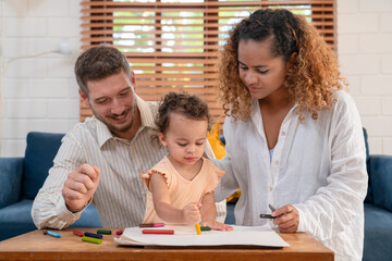 Obraz premium Enjoy happy smiling love family father and mother with little girl learning and writing in book with pencil making homework at home. Education concept 