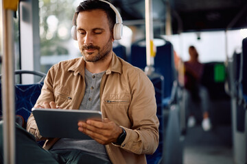 Male commuter surfing the net on touchpad while riding in a bus.