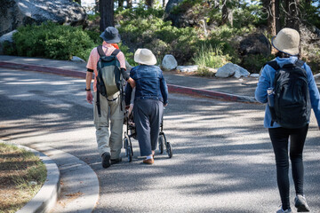 Senior woman walking with a mobility walker, accompanied by son and daughter. Lake Tahoe....