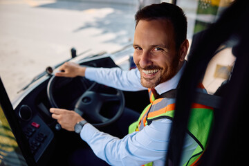 Happy bus driver inside vehicle cabin looking at camera.
