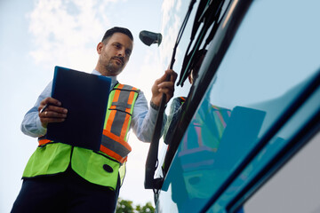 Below view of bus driver examining  vehicle before  ride. © Drazen