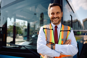 Happy driver with crossed arms in front of bus looking at camera.