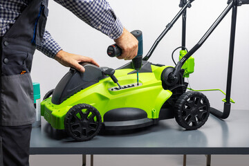 Lawnmower repair. The man is repairing the mower in the work shop.