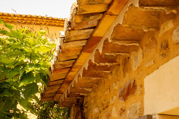 Mediterranean roof tiles and stone wall. Partial view from below