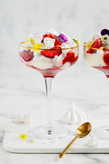 Eton mess - traditional english dessert with meringue, whipped cream and fresh strawberries  in a glasses on a light background. Selective focus