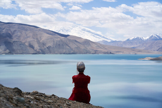 rear view of an Uyghur lady sitting and overlooking Baisha Lake in Xinjiang, China