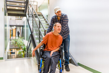 Man assisting a coworker with disability walking along a corridor