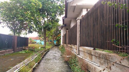 the flow of water in a large ditch in a residential area of ​​a village