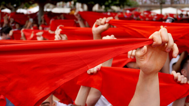 People hold red scarves with their hands raised. Inauguration during the celebration of San Fermin, in the city of Pamplona, ​​Spain. June 6, 2024