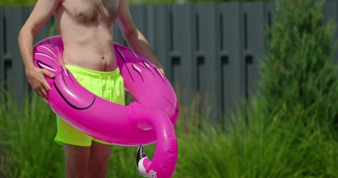 A man in an inflatable bird-shaped float with the birds neck rising upward, symbolizing an erection.