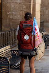 Fototapeta premium Detail shot of a pilgrim on his back with his large backpack on his back and the characteristic shell of the Camino de Santiago.