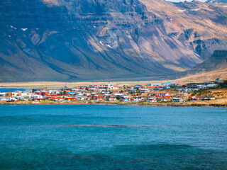 Fototapeta premium Charming coastal town with colorful houses nestled against majestic mountains in Iceland