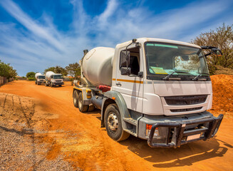 concrete mixer trucks on a dirt road on construction site