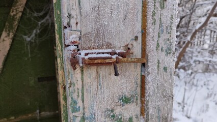 Latch in frost on an old wooden barn or toilet door