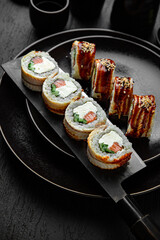 Canada Roll with salmon and Smoked Eel. Sushi composition on black background. The Art of Japanese Cuisine. Food photography for menu and sushi bar decoration