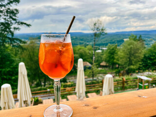 Aperol glass syringe on a background of greenary landscape.