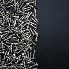Closeup of steel screws on black background with copy space