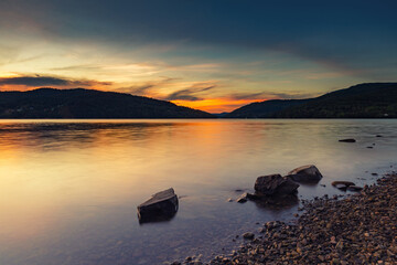 Krajobraz wodny i żaglówki nad jeziorem, letni zachód słońca, piękny kolor, kolorowe niebo i chmury, kształt sylwetki, widok na taflę wody, dzikie wybrzeże, Jezioro Żywieckie w górach © anettastar