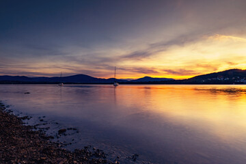 Krajobraz wodny i żaglówki nad jeziorem, letni zachód słońca, piękny kolor, kolorowe niebo i chmury, kształt sylwetki, widok na taflę wody, dzikie wybrzeże, Jezioro Żywieckie w górach © anettastar