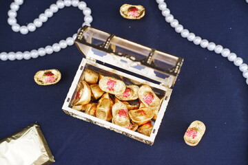 Box filled with gold coins on black surface, symbolizing wealth and prosperity