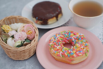 pink plate with a donut and a cup of tea on top, perfect for a cozy afternoon snack.