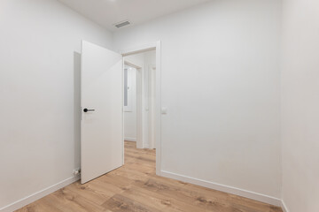 Empty modern room with open door and wooden floor offers clean stylish space for buyers or renters