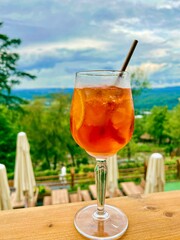 Aperol glass syringe on a background of greenary landscape.