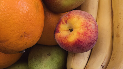 close-up of assorted fruits, including a vibrant peach, orange, and bananas