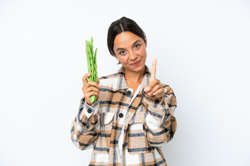 Young hispanic woman holding a green beans isolated on white background showing and lifting a finger