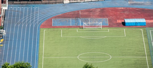 Aerial view of an empty sports field with a track and soccer field on a sunny day