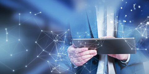 A businessman using a tablet with network connection graphics overlay, digital concept on a blurred blue background