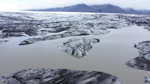  Aerial drone view of rapid melting glaciers and icebergs in Iceland due climate change and global warming. Fjallsarlon glacier

