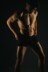 Fit man showing his abs in dark lighting, depicting fitness, strength, and dedication