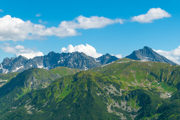 Fototapeta premium Beautiful mountain landscape in summer. Green grass, high rocks, blue sky and white clouds. Natural background. Tatra Mountains