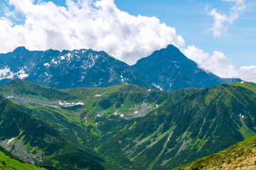 Obraz premium Beautiful mountain landscape in summer. Green grass, high rocks, blue sky and white clouds. Natural background. Tatra Mountains