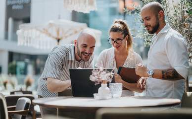 Business workers collaborating together on a project in a coffee bar, brainstorming ideas and sharing knowledge for solutions, working remotely.