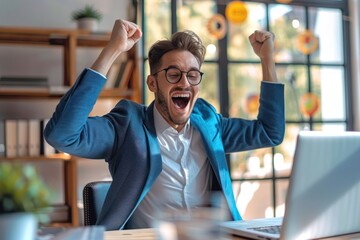 A young man in a blue blazer and glasses, cheering with excitement while looking at her laptop in a bright, cozy room