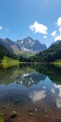 Fototapeta premium Mountain lake in a valley with green trees and blue sky