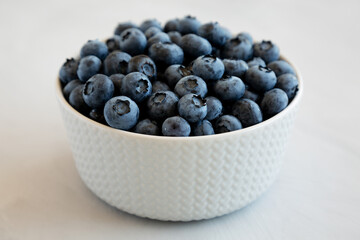 Organic Blueberries in a Bowl on a gray background, side view.