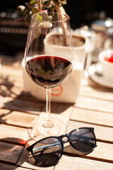 glass of Georgian red wine and sunglasses on table