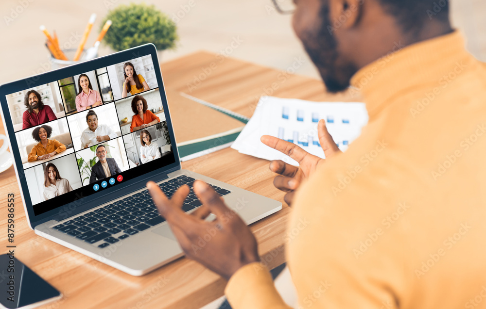 Aufkleber black man sitting at a desk in front of a laptop, participating in a video conference with his colle