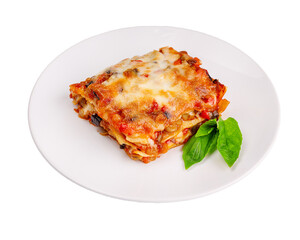 Close-up of a traditional lasagna made with minced beef bolognese sauce topped with basil leafs served on a white plate