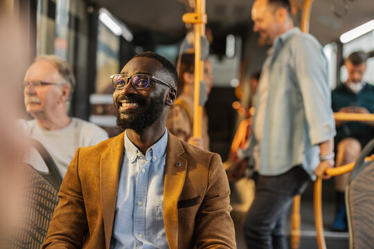 Man smiling on a bus during a full bus ride at rush hour - Powered by Adobe
