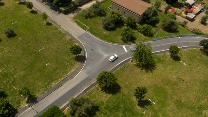 Aerial view on a three-way intersection. A white car sits in the middle.