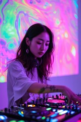 A young woman with long dark hair is focused on mixing music on a DJ mixer in a studio with neon lights.