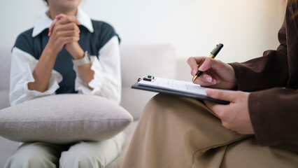 Professional psychotherapist  with clipboard listening attentively to her patient during therapy Session. Advice, assistance and mental health concept.